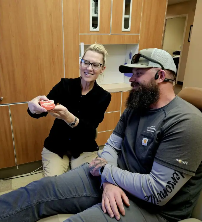 Dentist explaining deep cleaning steps with a tooth model